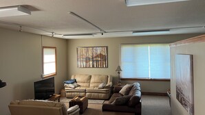 Una sala de estar con un sofá color beige, un sofá marrón, una mesa de centro, un televisor y una lámpara.