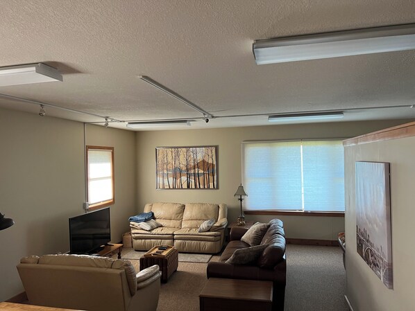 A living room with a beige sofa, a brown sofa, a coffee table, a TV, and a lamp.
