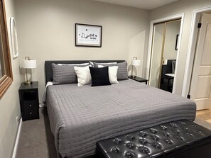 A bedroom with a bed, bedside tables, a bench, and a framed quote on the wall.