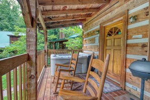 Una terraza de madera con un jacuzzi, sillas de madera y una parrilla.