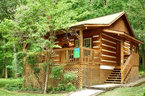 A wooden cabin with a covered porch and a staircase leading to the entrance.