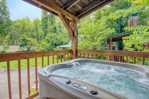 A hot tub on a wooden deck with a view of a forested area.