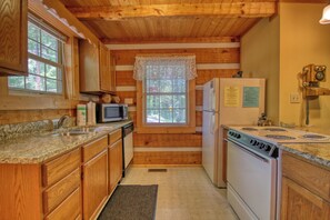 A wooden cabin kitchen with granite countertops, a white stove, and a vintage telephone.