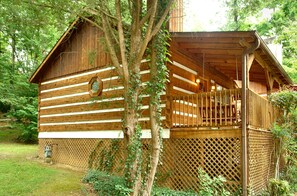 Una cabaña de madera con balcón, rodeada de árboles y una valla de madera.