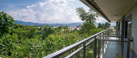 A balcony with a view of lush greenery and distant mountains.