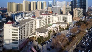 A large hotel with a central courtyard, surrounded by high-rise buildings and a parking lot.