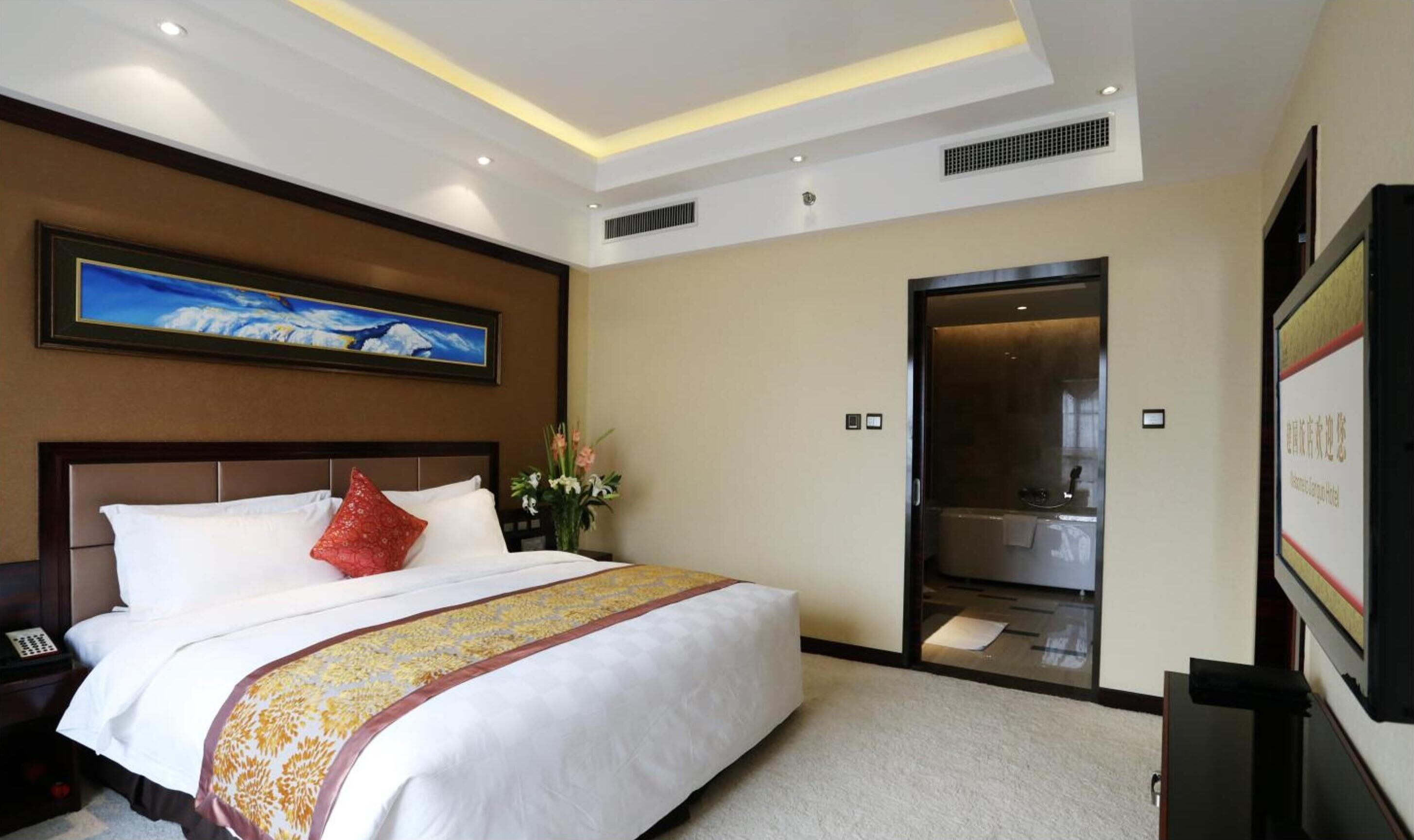 Ein Hotelzimmer mit einem großen Bett, einem Bild an der Wand, einer Duschkabine und einem Fernseher.