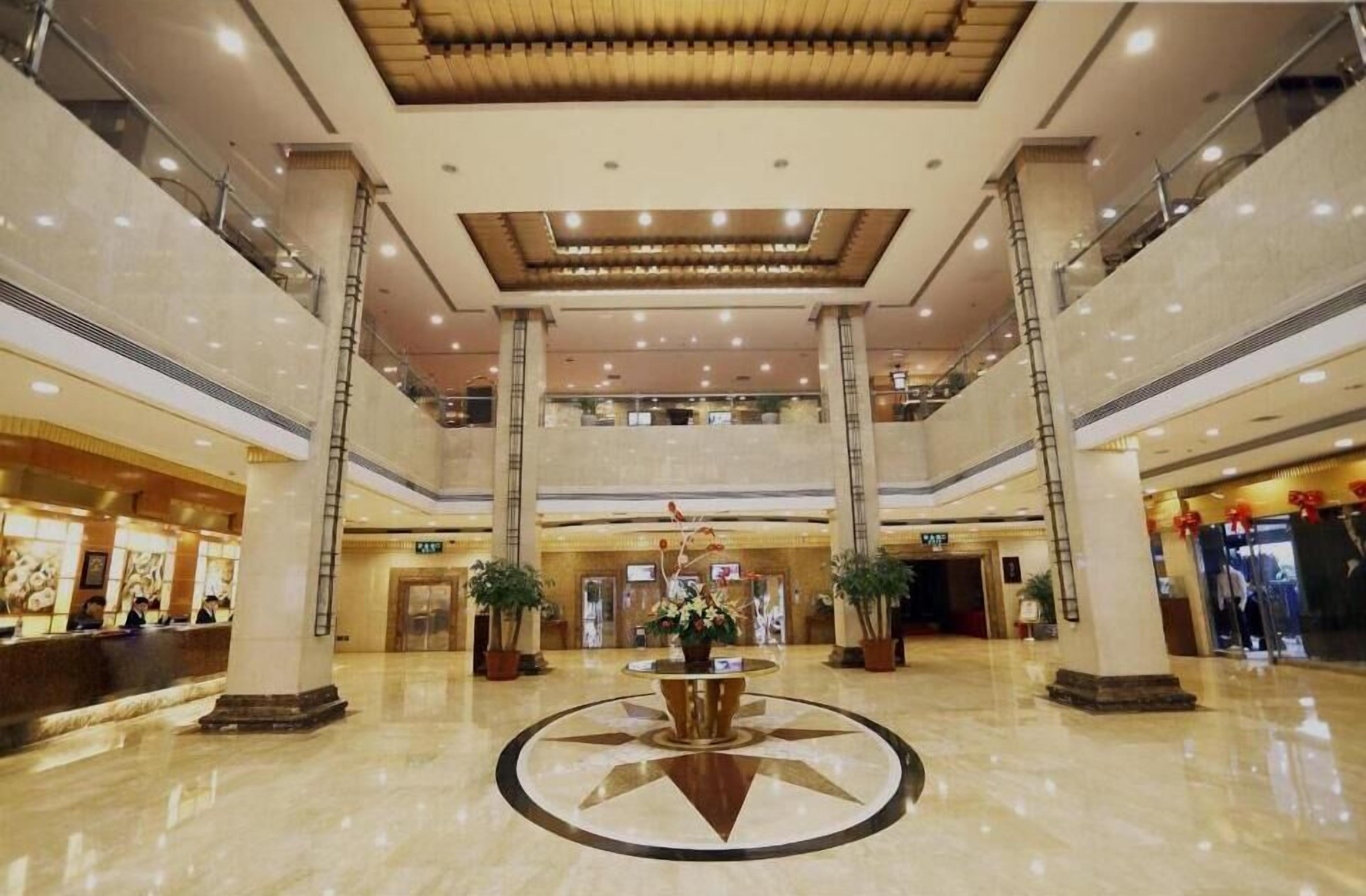 A spacious lobby with a central decorative fountain, multiple levels, and a reception desk.