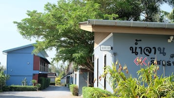 A building with a blue exterior, a sign with a number, and a wall with text and symbols.