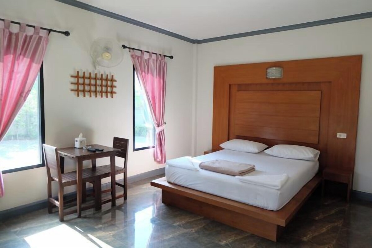 A bedroom with a wooden bed frame, a bedside table, and a chair.