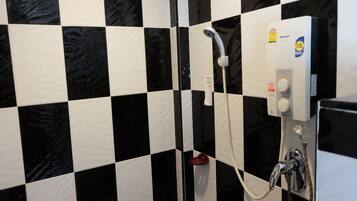 A bathroom with black and white checkered tiles, a white showerhead, and a control panel with a Panasonic logo.