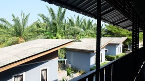 A row of single-story buildings with flat roofs, surrounded by lush greenery and palm trees. - Numjaan Resort (Krabi)