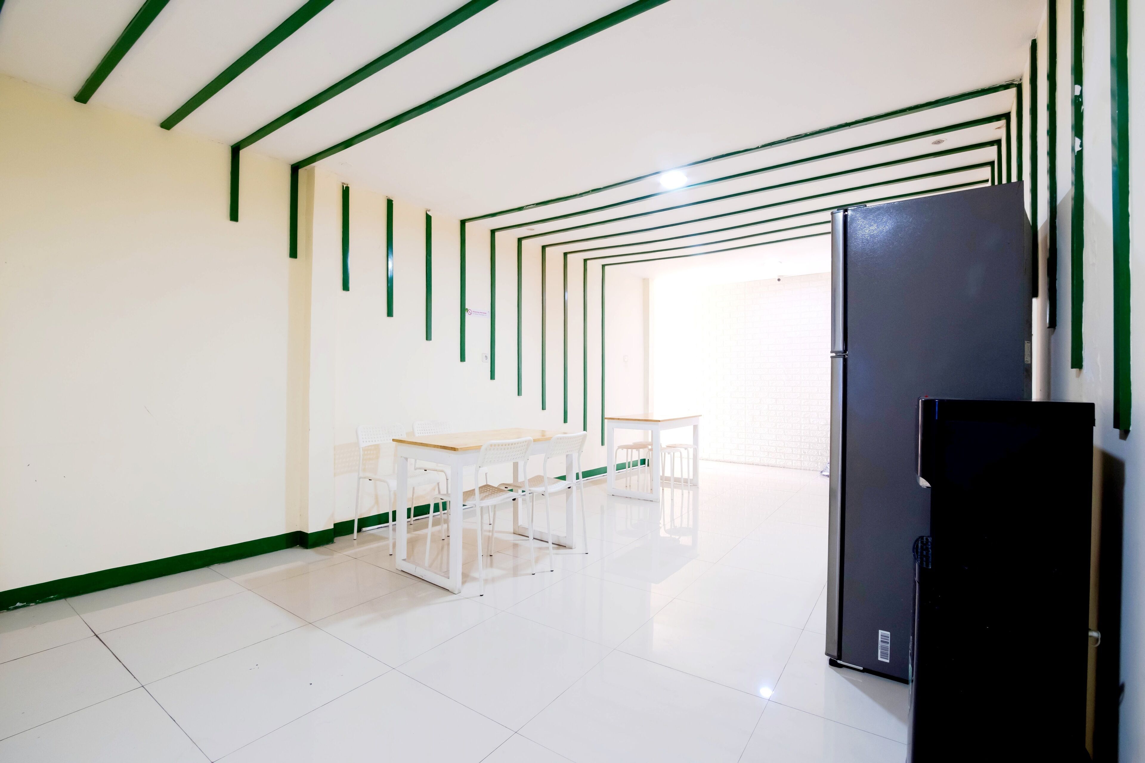 A modern kitchen with white cabinets, a black refrigerator, and a dining area with a table and chairs.