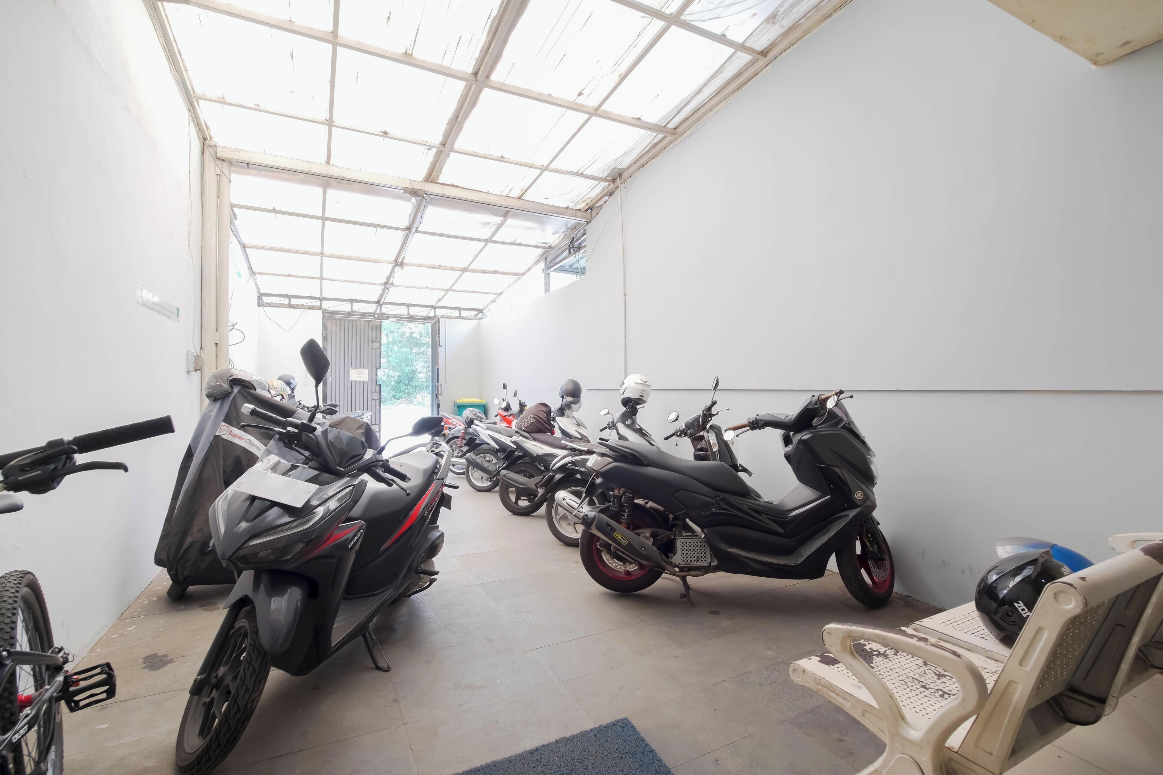 A motorcycle repair shop with several motorcycles lined up, a bicycle, and a few chairs.