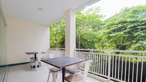 A balcony with a table and chairs, a railing, and a view of lush greenery. - Le Paris Syariah Residence (Tangerang)