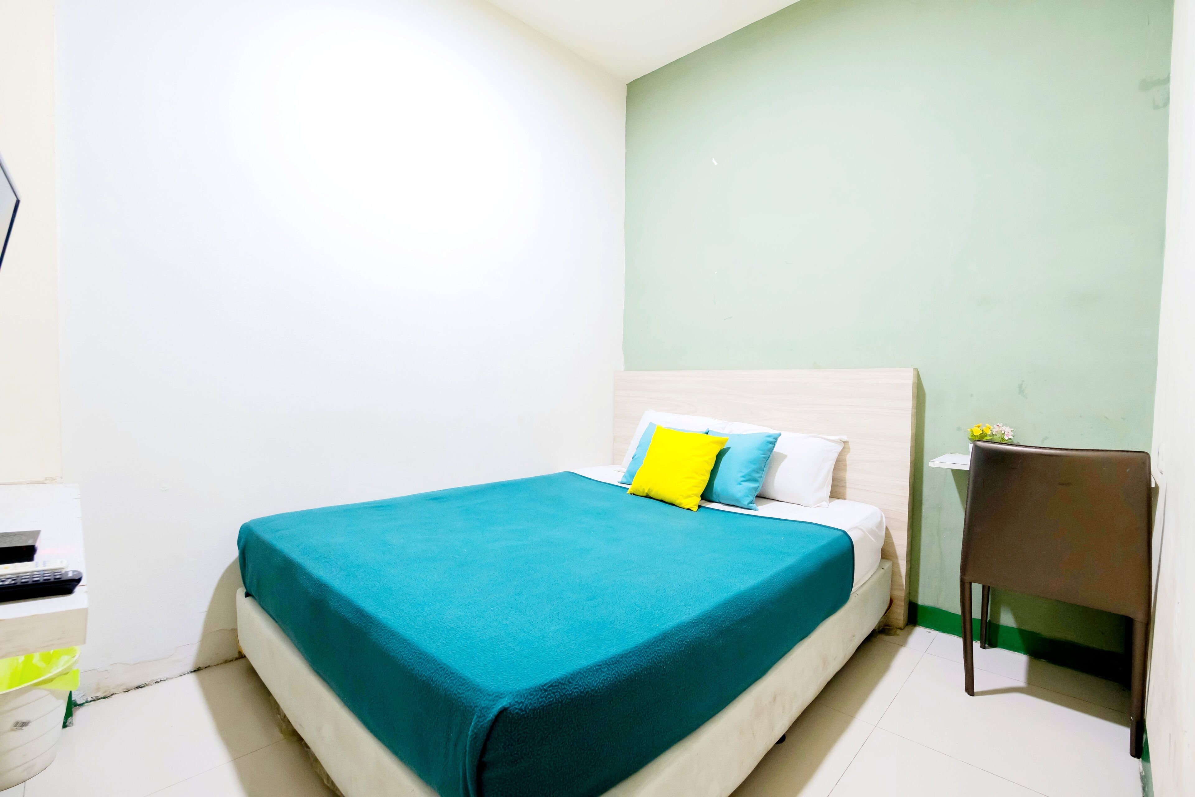 A bedroom with a bed, a bedside table, and a chair.