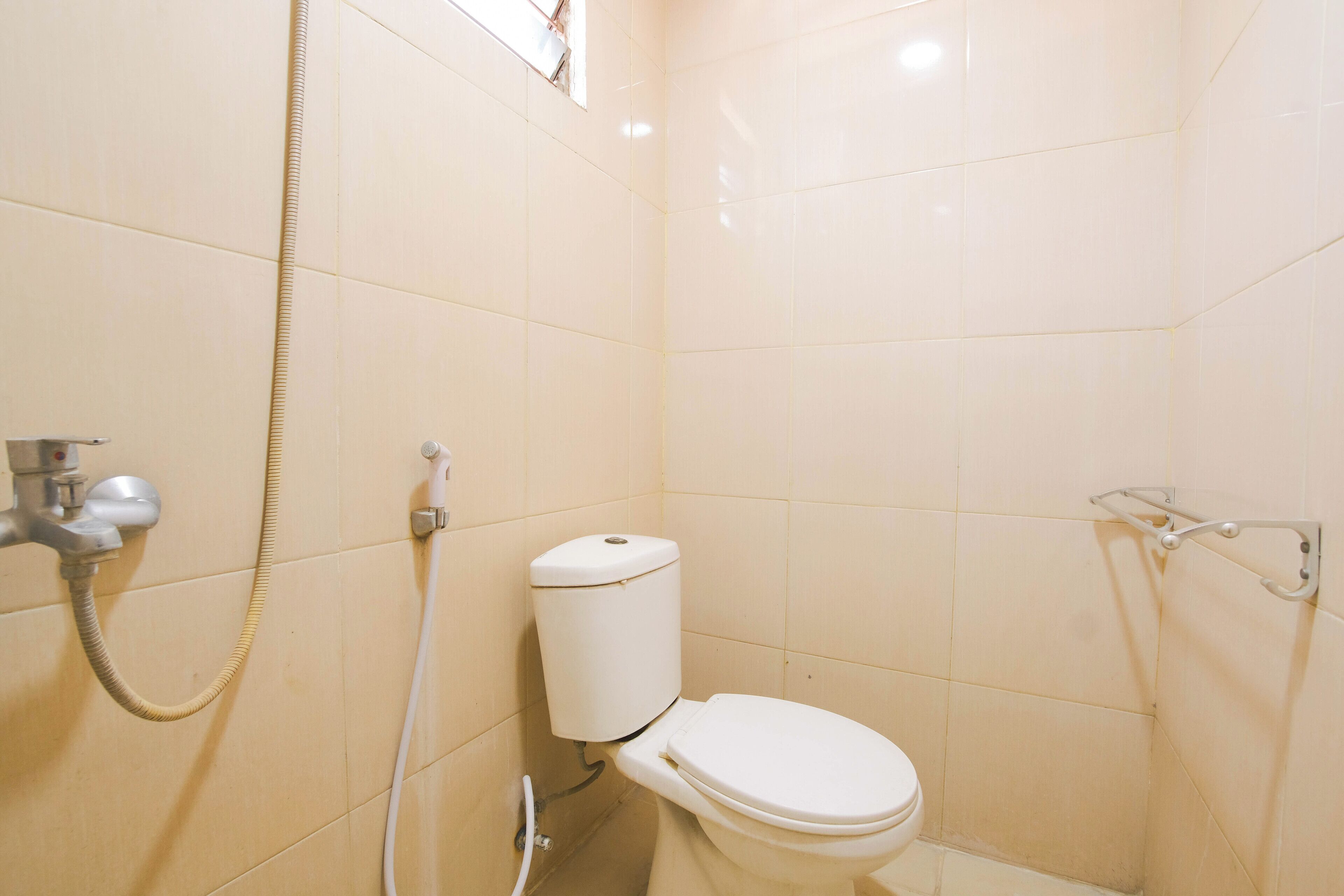 A small, clean bathroom with a toilet, a shower, and a handrail.