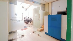 A reception area with a glass door, a blue counter, and a motorbike parked outside. - Le Paris Syariah Residence (Tangerang)