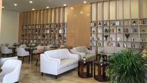 A modern lobby with a white sofa, multiple seating areas, and a large bookshelf filled with books. - Qinghai Baiyun Xiangling Hotel (Xining)