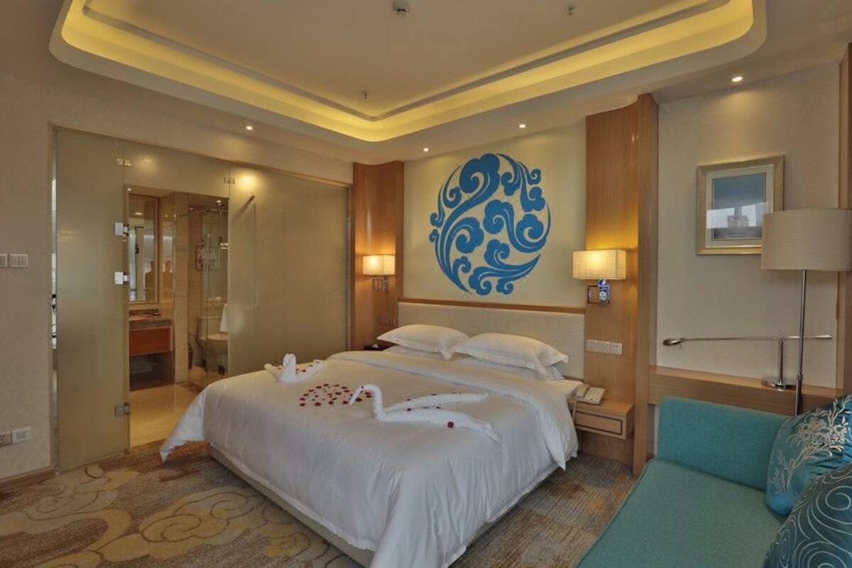 Une chambre d’hôtel avec un grand lit, une salle de bain et un coin salon.
