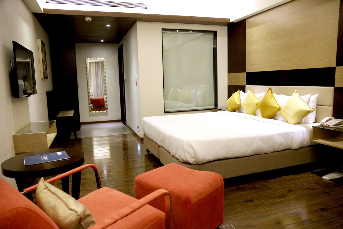 A hotel room with a bed, a desk, a chair, and a large window.