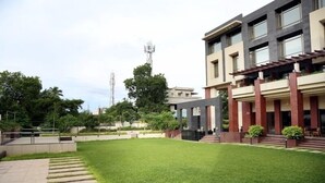 A modern building with a well-maintained lawn and steps leading to the entrance. - Hotel Shakti Continental (Angul)