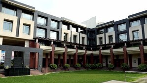 A modern building with a courtyard, featuring a central open space with steps leading up to a covered area. - Hotel Shakti Continental (Angul)