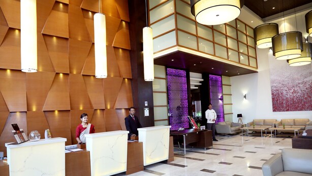A hotel reception area with marble reception desks, a seating area with sofas, and a modern interior design. - Hotel Shakti Continental (Angul)