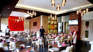 A spacious restaurant with multiple dining tables, chairs, and a modern chandelier. - Hotel Shakti Continental (Angul)