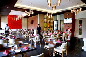 Un restaurante espacioso con varias mesas, sillas y un moderno candelabro.