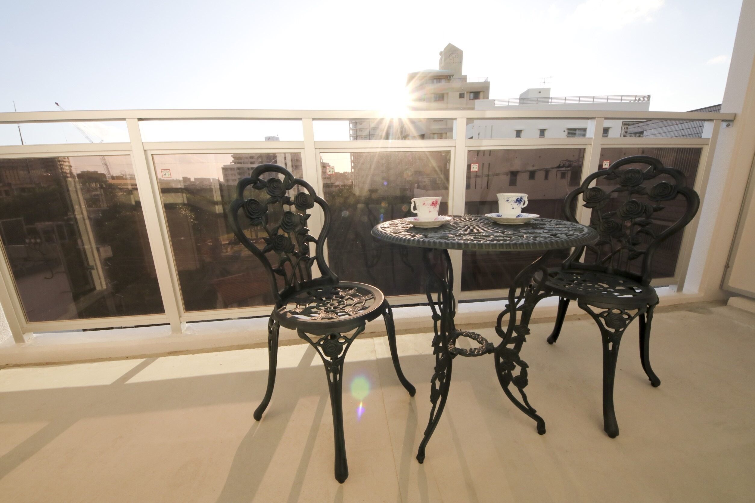 Un balcon avec une table et des chaises, une tasse et une soucoupe.