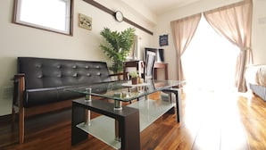 A modern living room with a leather sofa, glass coffee table, and a potted plant. - Chura Gahna House Tsubogawa Naha (Naha)