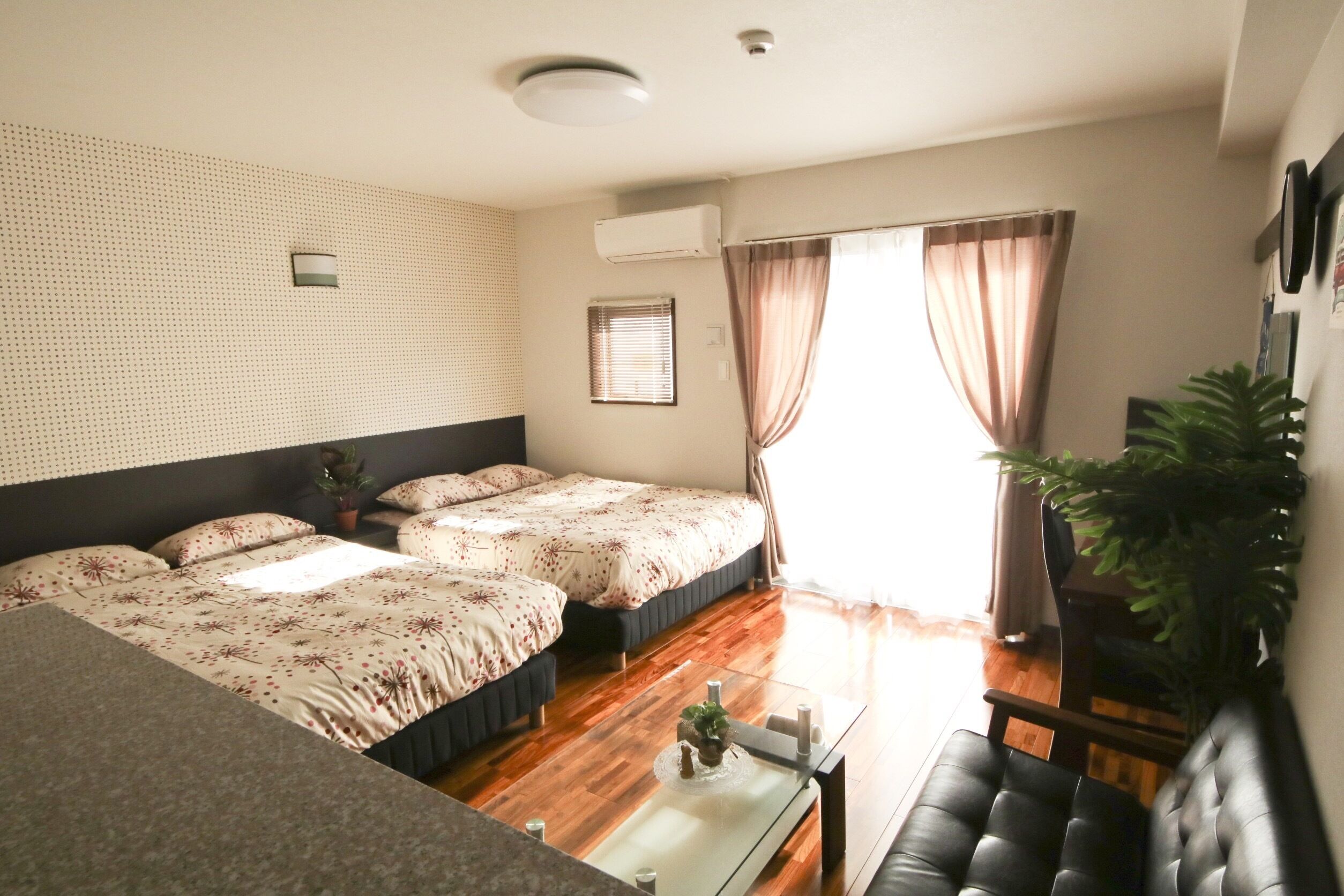 Une chambre moderne avec deux lits, un canapé, une petite table et une plante en pot.
