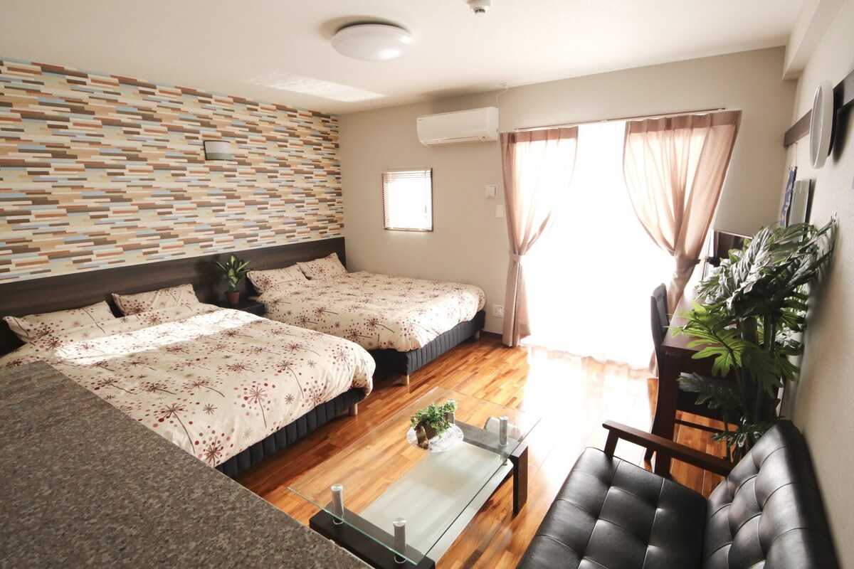Una habitación de hotel con dos camas, un sofá, una mesa de centro y una planta en maceta.