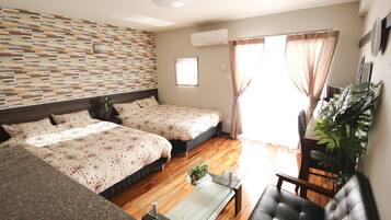 A hotel room with two beds, a sofa, a coffee table, and a potted plant.