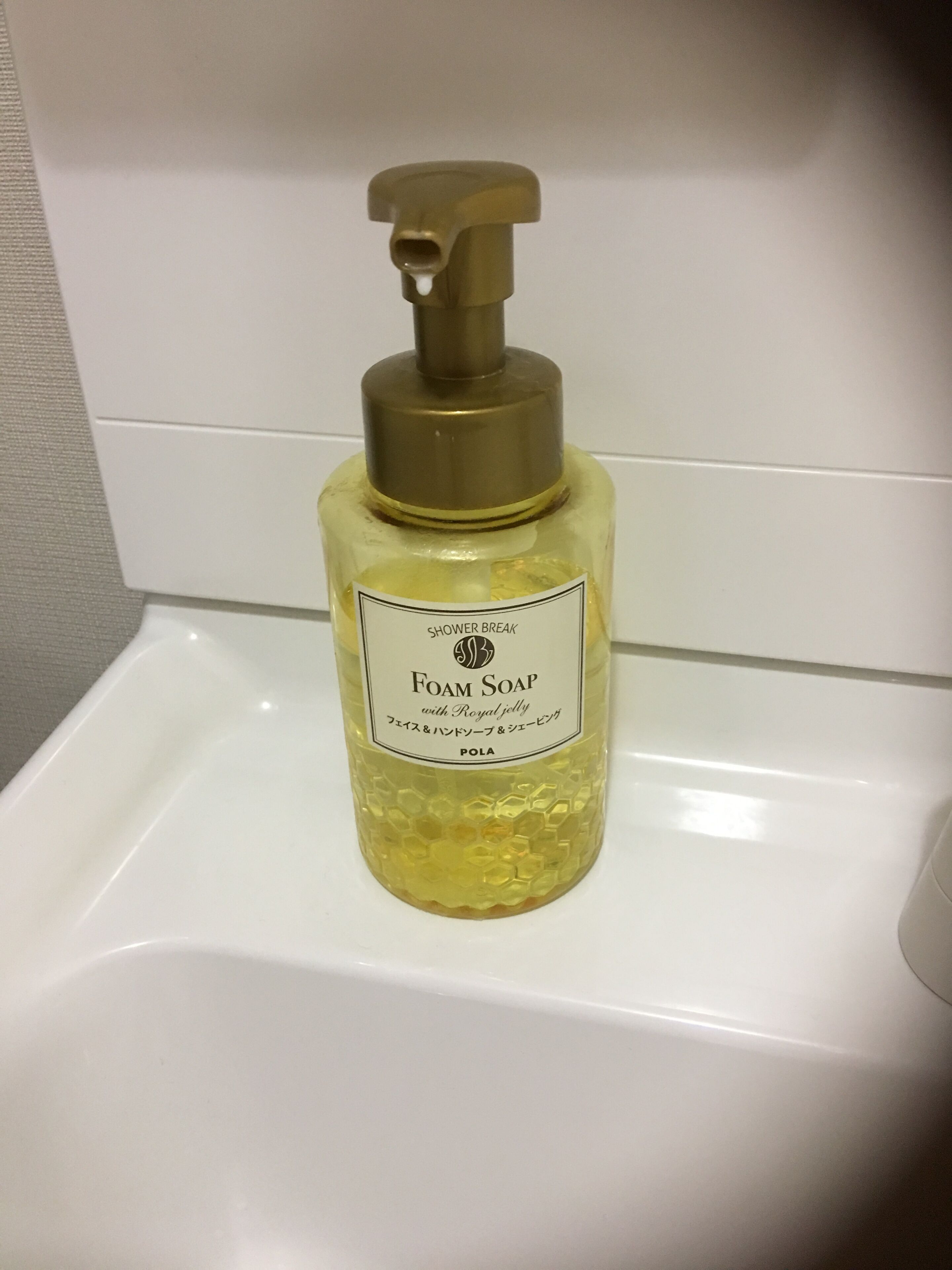 Una bottiglia di sapone schiumogeno con erogatore a pompa su un lavandino bianco.