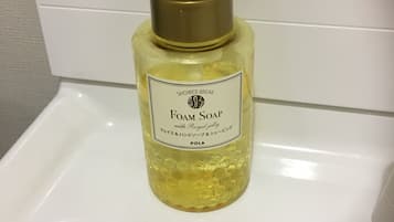 Una bottiglia di sapone schiumogeno con erogatore a pompa su un lavandino bianco.