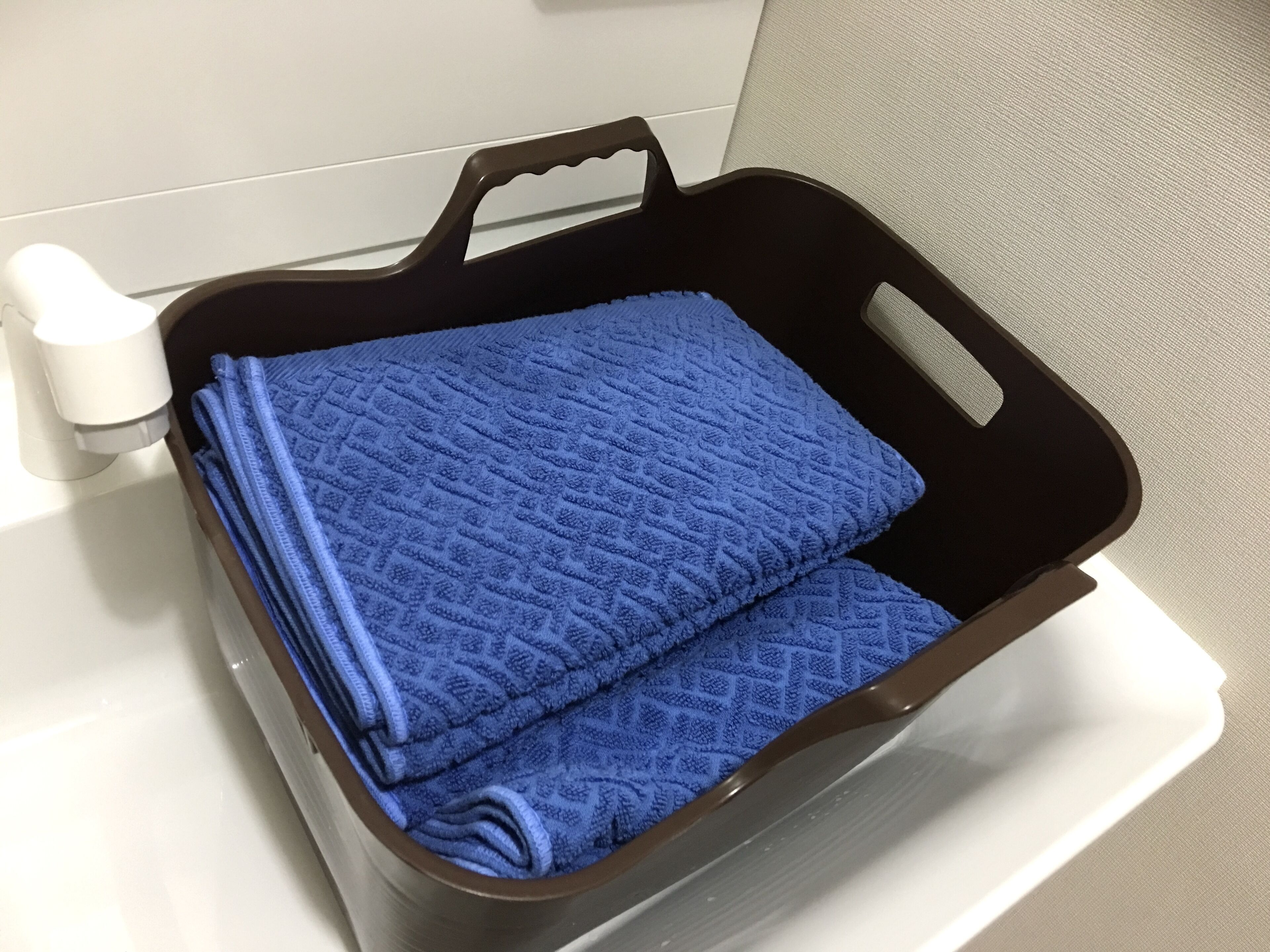 Een badkamer met een zwarte badmat houder met een opgevouwen blauwe badmat.