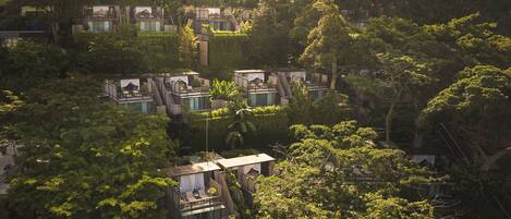 A cluster of modern, multi-story buildings nestled among dense foliage, featuring balconies and terraces.