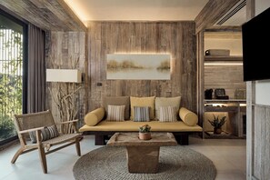 Un salon moderne avec un panneau mural en bois, un canapé avec des coussins, un fauteuil, une table basse et un téléviseur à écran plat fixé au mur.