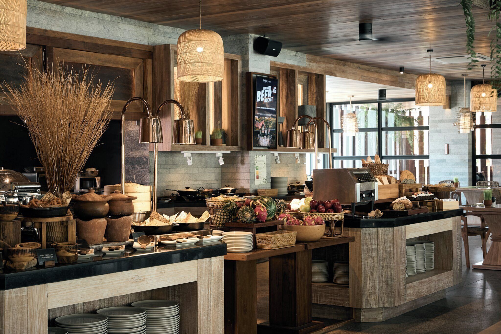 A rustic kitchen with wooden countertops, hanging lights, and a variety of fruits and vegetables displayed.