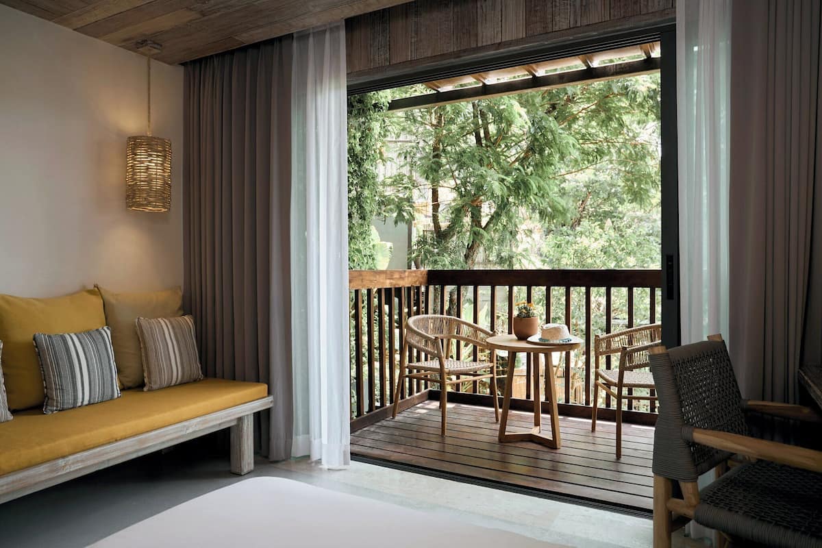 A balcony with a wooden bench, wicker chairs, and a table with a potted plant.