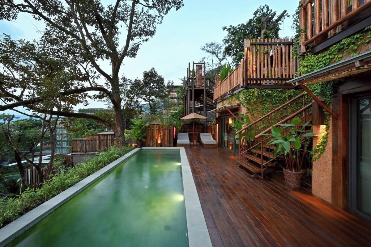 Un espace piscine extérieur moderne, doté d’une terrasse en bois, d’un escalier et d’une végétation luxuriante.