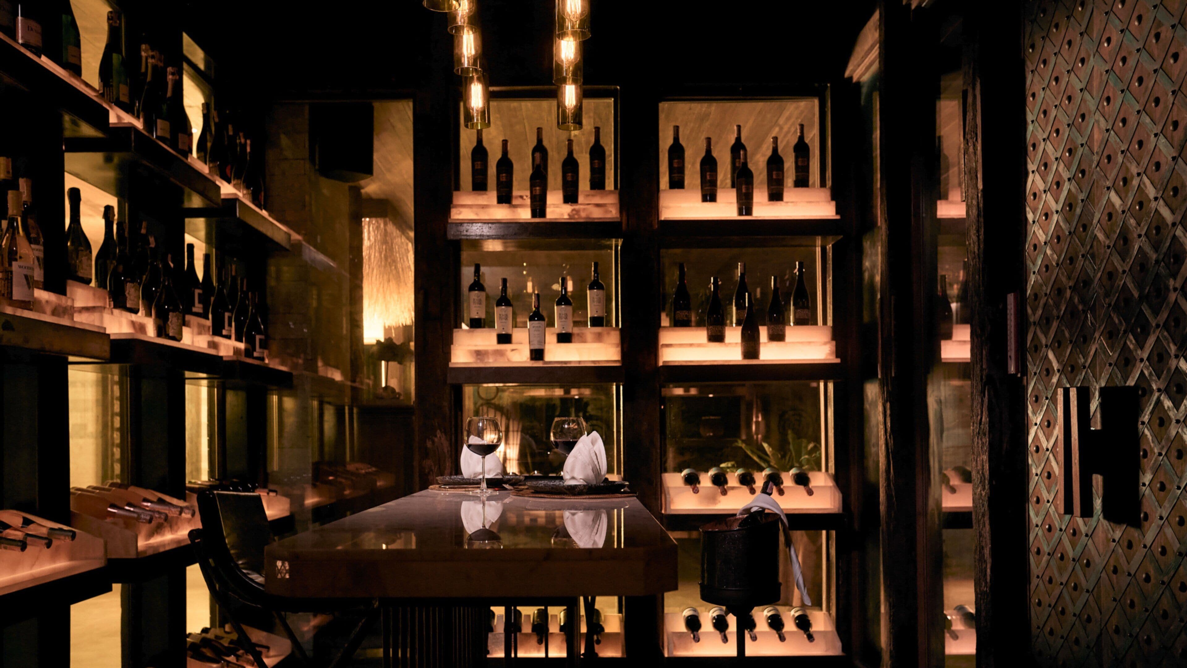 A bar with shelves of bottles, a bar counter, and a seating area.