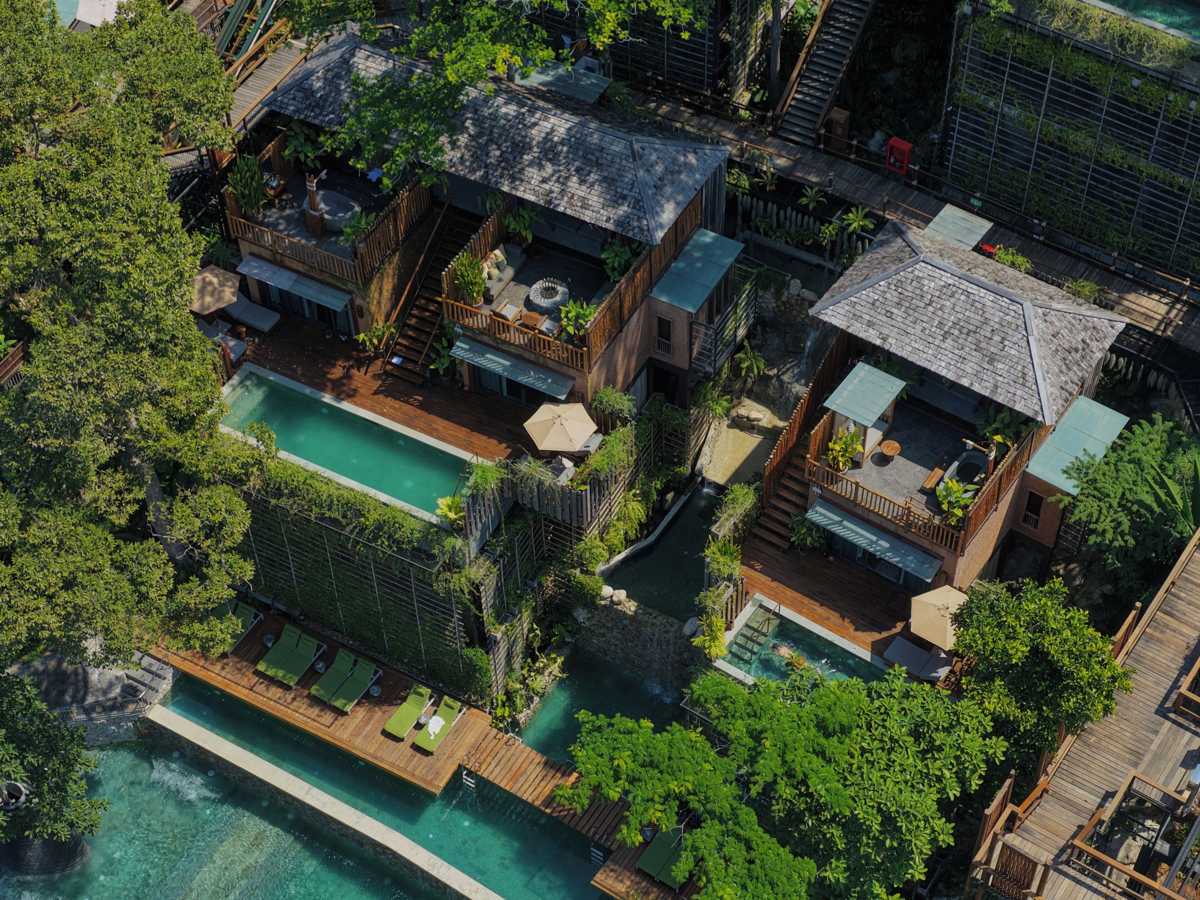 An aerial view of a resort with multiple buildings, a swimming pool, and lush greenery.