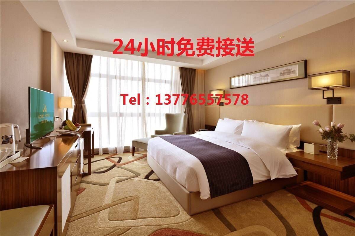A hotel room with a bed, bedside tables, a desk, a chair, and a television.