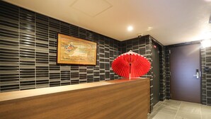 A reception desk with a wooden finish, a framed artwork above it, and a red decorative umbrella to the right.