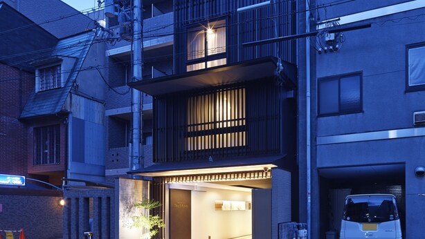 A multi-story building with a ground-level entrance, a parking area, and visible electrical infrastructure.
