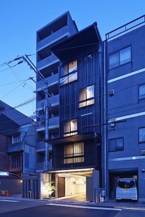 A multi-story building with a ground-level entrance, a parking area, and visible electrical infrastructure.