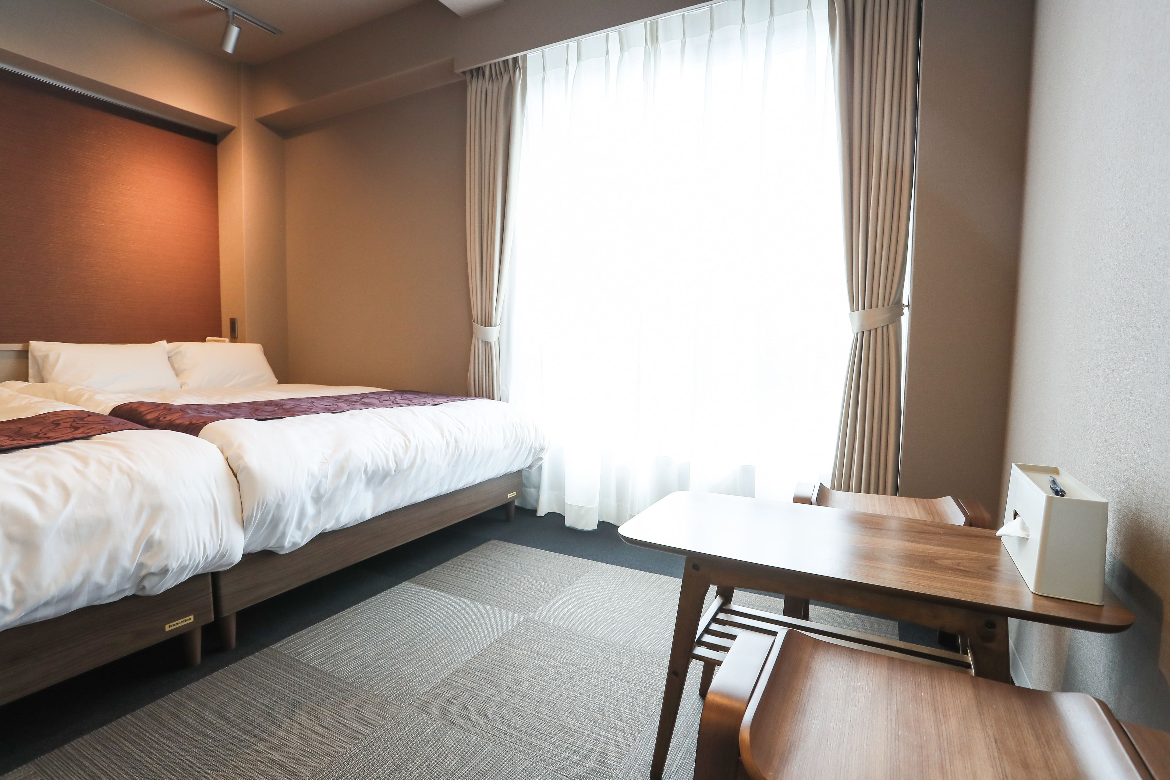 A hotel room with a bed, a desk, and a chair.